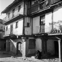 Salamanca, Casas de estructura de madera y encaladas con balconadas en La Alberca. Aparece una mujer sentada.